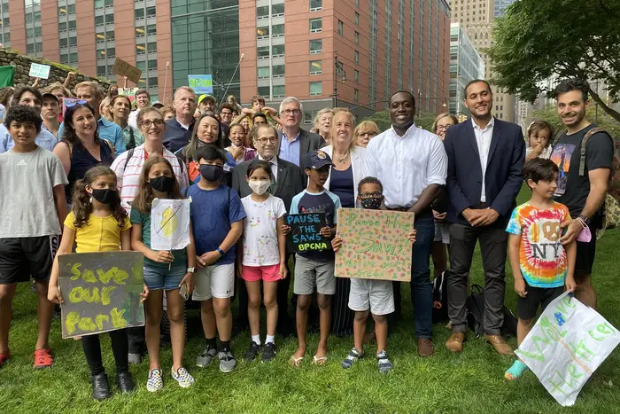 Photograph of about 30 children and adults with elected officials like Rep. Nadler and Manhattan BP Brewer on the lawn in Battery Park City